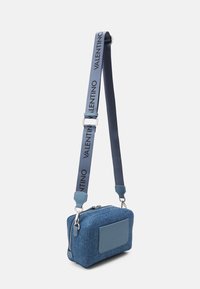 Denim axelväska med rektangulär form, blå färg, slät textur, märkesrem och dragkedjestängning. Har läderdetaljer.