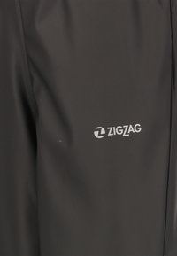 Svarta vattentäta byxor med en slät yta, rak passform och en liten vit ZigZag-logotyp på vänster sida.