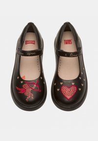 Czarne skórzane buty typu Mary Jane z paskiem, ozdobione kolorowymi wzorami jednorożców i serc oraz napisem "Dawno, dawno temu" napisanym kursywą.