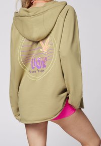 Sweat à capuche kaki avec un grand motif coloré représentant des vagues et un design de feuille au dos. Matière douce, coupe décontractée.