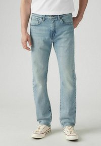 Helle blauen Denim-Jeans mit geradem Bein, fünf Taschen und klassischem Knopfverschluss. Tragen mit weißen Sneakers.