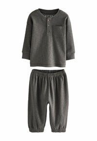 Camisa gris de manga larga con textura acanalada, un bolsillo y tres botones en el escote, combinada con pantalones grises de cintura elástica y puños fruncidos.