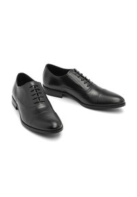 Pantofi de piele negri cu vârf ascuțit, șase gauri pentru șireturi, detalii subtile de cusătură și o textură netedă pe un toc mic.