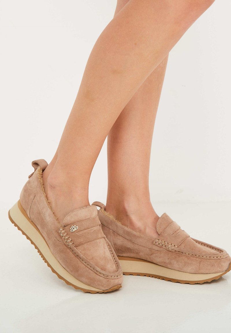 Mocasines de ante en beige claro con un acabado texturizado, que presentan un detalle de costura en la parte superior y una suela de goma para mayor agarre.