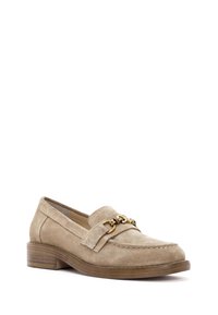 Mocasines de ante beige con tacón plano, que presentan una cadena decorativa en tono dorado a lo largo del empeine y detalles de costura en los bordes.