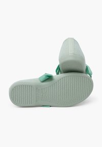 Zapatillas casuales de malla verde con suelas de goma, que presentan un fondo texturizado y acentos verdes a juego en los laterales. Fabricadas en España.