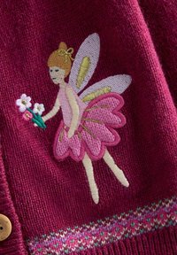 Stickad cardigan i djup rosa med broderad fe i en rosa klänning som håller blommor. Har intrikata stygn och mönstrad kant.