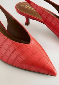 Röda, spetsiga slingback-höga klackar gjorda av syntetiskt material med krokodilmönster. Har en liten, kraftig klack och en utskärningdesign.