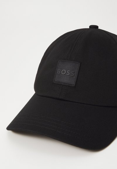 Casquette de baseball noire en tissu texturé, dotée d'un patch noir carré avec le logo "BOSS" en relief. Visière courbée et accents cousus.