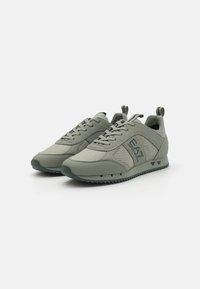 Scarpe sportive di un grigio chiaro con un mix di pelle liscia e rete. Presentano una suola testurizzata e un dettaglio con il logo sul lato.