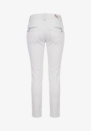 Pantaloni bianchi aderenti visti da dietro con tasche con cerniera, passanti per cintura e una piccola toppa floreale sulla cintura.