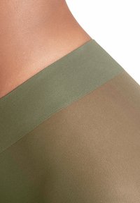 Olive zielone legginsy z teksturowanym pasem, z przezroczystą górną warstwą i solidną, nieco ciemniejszą dolną częścią.