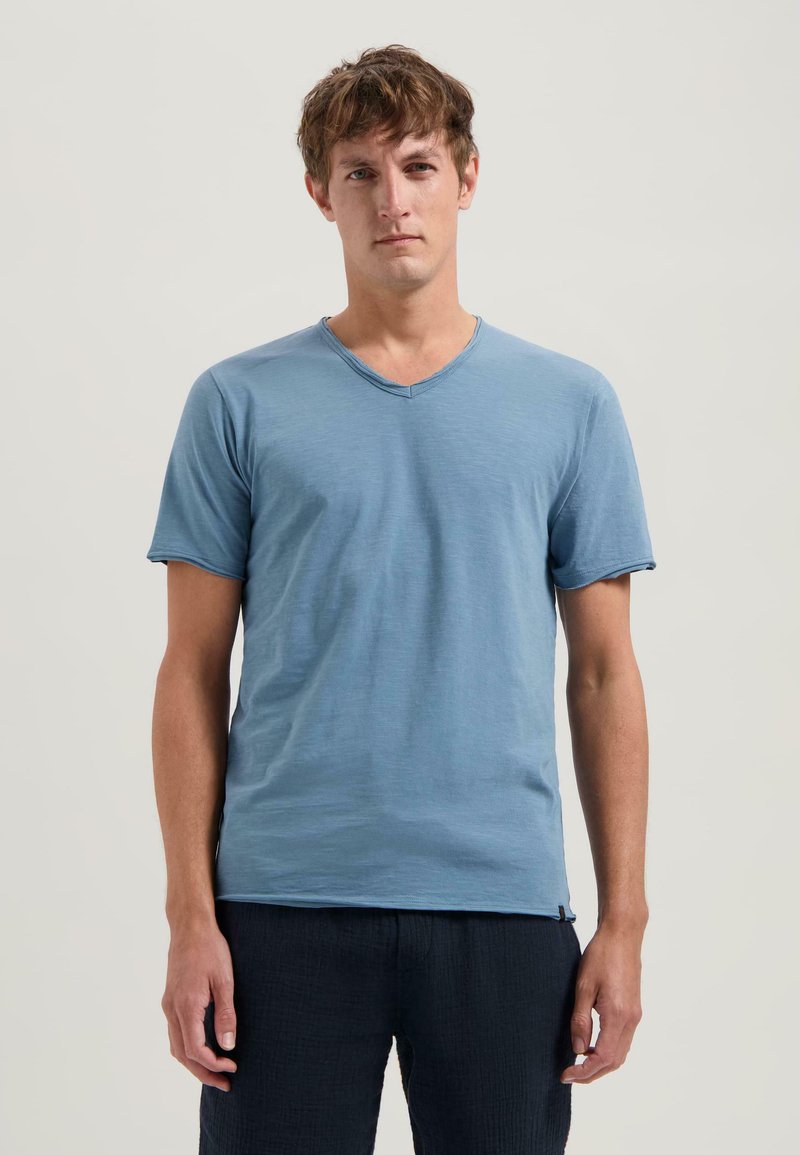 Blå kortärmad t-shirt med v-ringning, gjord av mjukt tyg och med en avslappnad passform. Notabel detalj inkluderar en subtil textur i materialet.