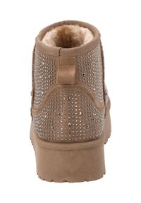 Bottine marron en matériau doux, avec un intérieur doublé, recouverte de petites clous en argent, dotée d'une semelle en caoutchouc texturée.