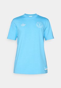 Light blue cotton t-shirt with short sleeves, round neck, embroidered Adidas logo on the left chest, and a patch at the bottom.