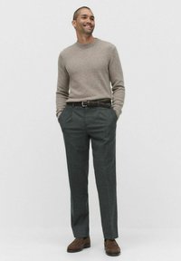 Jasnobrązowy sweter wełniany, ciemnoszare spodnie, pleciony czarny pasek, brązowe buty; minimalistyczny design, miękka tekstura i dopasowany krój.