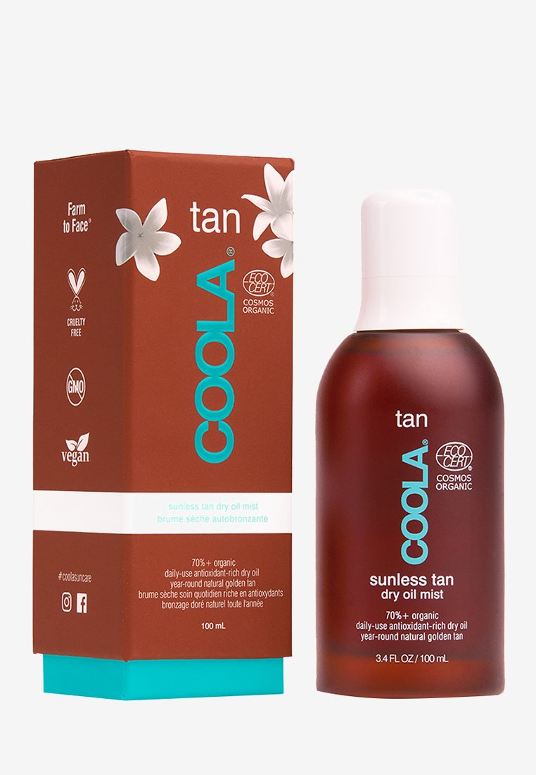 Brązowa szklana butelka z białą zakrętką, oznaczona etykietą "COOLA sunless tan dry oil mist". W komplecie z pasującym brązowym pudełkiem tekturkowym.