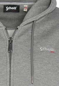 Sudadera con cremallera en color gris, hecha de una mezcla de algodón, que presenta una cremallera plateada, cordones y un logotipo bordado en rojo en el pecho.