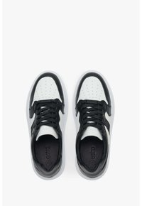 Czarno-białe sneakersy z perforowanym białym noskiem, czarnymi skórzanymi akcentami, płaskimi czarnymi sznurowadłami i teksturowaną czarną wkładką wewnętrzną.