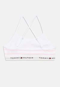 Balta kokvilnas krūšturis ar rozā horizontālām svītrām un zīmola elastīgu joslu. Tajā ir krusteniskas regulējamas lencītes un gluda tekstūra.