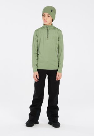 Camicetta verde a maniche lunghe con collo a zip, pantaloni neri e berretto coordinato. La camicia presenta un marchio sottile e una texture liscia.
