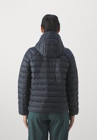 Gefütterte, dunkelblaue Jacke mit Kapuze, die ein gestepptes Design, lange Ärmel und elastische Manschetten aufweist. Glattes, glänzendes Gewebe mit einer weichen Textur.