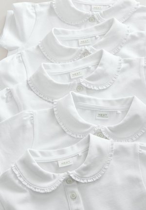 Four white collared shirts with ruffled edges stacked neatly, featuring button closures and tags visible on the collars.
