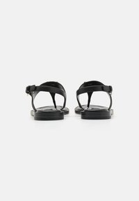 Zwarte leren sandalen met een minimalistisch ontwerp, voorzien van enkelbandjes en platte zolen. Verstelbare gespverbinding bij de enkel.