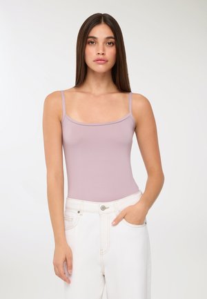 Top fitted lilac con spalline sottili, texture liscia e scollatura quadrata, abbinato a jeans bianchi a vita alta.