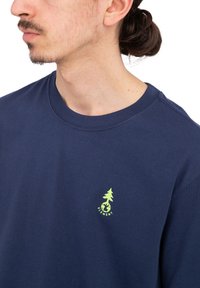 Navy blue cotton t-shirt featuring a small green tree logo on the chest, round neckline, and a relaxed fit. Soft, smooth texture.