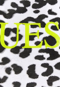 Černobílý materiál s leopardím vzorem a velkým neonově žlutým nápisem "QUEST." Design obsahuje texturovaný tečkovaný vzor.