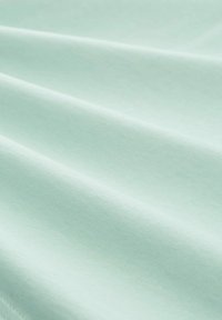 Tessuto verde menta con una texture liscia e una leggera lucentezza, che mostra pieghe e grinze delicate. Il materiale appare leggero e traspirante.