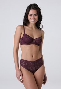 Set di reggiseno in pizzo bordeaux e slip a vita alta con motivi floreali, spalline regolabili e bordi ondulati. Tessuto morbido e trasparente.