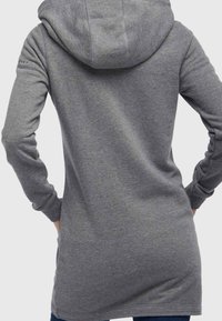 Grijze, lange hoodie met een capuchon, met een gladde textuur, lange mouwen en een afgeronde achterkant. Geen zichtbare logo's of patronen.