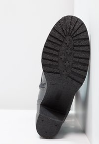 Černá gumová podrážka s texturovaným vzorem pro zajištění gripu a patou. Vyztužené okraje a hladké strany v šedém materiálu. Ideální pro trakci.