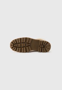 Semelle de botte en caoutchouc marron avec des motifs de semelle profonds pour une meilleure adhérence, forme arrondie et bord lisse avec des accents surélevés.