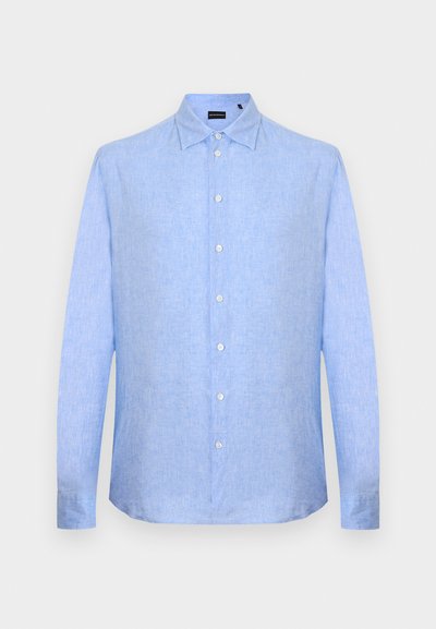 Ανδρικό πουκάμισο σε ανοιχτό γαλάζιο χρώμα με μακριά μανίκια, εμπρός με κουμπιά και κλασικό γιακά, σε απλό ανοιχτό γκρι φόντο.