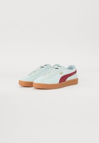 Lys blå semsket sneakers med en rød side stripe, beige gummisåle, flate lisser og gullmerke. Minimalistisk design uten mønstre.