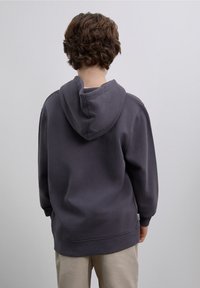 Gray hooded sweatshirt with a relaxed fit, featuring a kangaroo pocket and ribbed cuffs. Soft material with minimal stitching details.