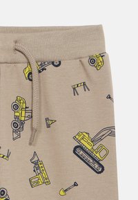 Μπεζ φόρμες με κορδόνι, με τυπωμένα κίτρινα κατασκευαστικά οχήματα και κώνους κυκλοφορίας. Απαλή ύφανση με λείο ύφασμα.