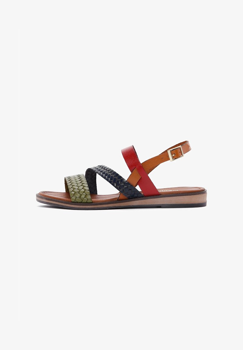 Multi-colored sandal with woven green, black, red, and brown leather straps, flat sole, and adjustable ankle buckle.