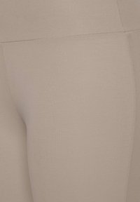 Beige Sportleggings aus einem glatten, dehnbaren Stoff mit einer engen Passform und flachen Nähten für Komfort. Keine sichtbaren Muster oder Akzente.