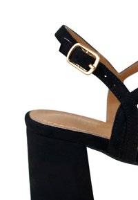 Black suede high-heeled sandal with a chunky heel, featuring an adjustable strap and gold-tone buckle accent. Smooth inner lining.