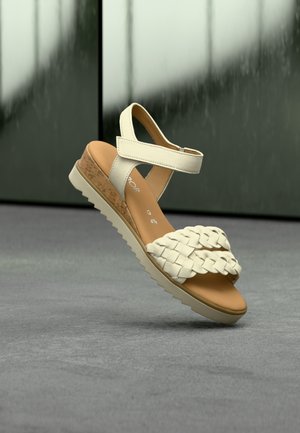 Λευκό σανδάλι από πλεγμένο δέρμα με φτέρνα σε σχήμα πλατφόρμας από φελλό, ρυθμιζόμενο λουράκι στον αστράγαλο και λαστιχένια σόλα. Διαθέτει υφή στην επάνω επιφάνεια και λείο πάτο.