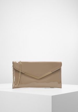 Pochette en cuir verni beige avec accent métallique doré en forme de V et fine chaîne dorée, posée sur un socle blanc sur fond uni.