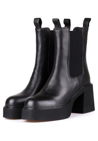 Botas de tobillo de cuero negro con paneles elásticos a los lados, suela de plataforma gruesa y tacón ancho. Textura suave con tiradores en bucle.