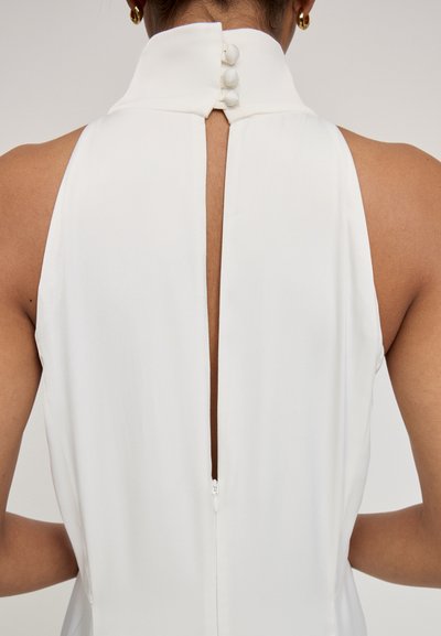 Vestido blanco sin mangas con un cuello alto que presenta una apertura en la parte posterior, asegurado con cuatro botones a juego, textura de tela suave, diseño minimalista.