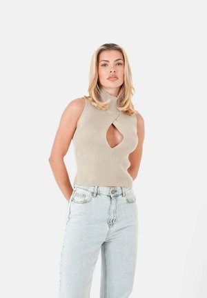 Débardeur beige en tricot sans manches avec col montant et découpe en forme de trou de serrure, associé à un jean droit en denim délavé. Texture lisse et motif côtes.