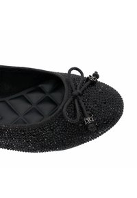 Zwarte balletschoenen met een gestructureerd oppervlak, voorzien van glanzende zwarte kraalversieringen en een decoratieve strik bij de teen. Zachte binnenvoering.