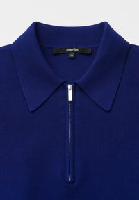 Polo en maille bleu marine avec fermeture éclair à l'avant, col structuré et texture côtelée. Étiquette indiquant "someday" taille 36.